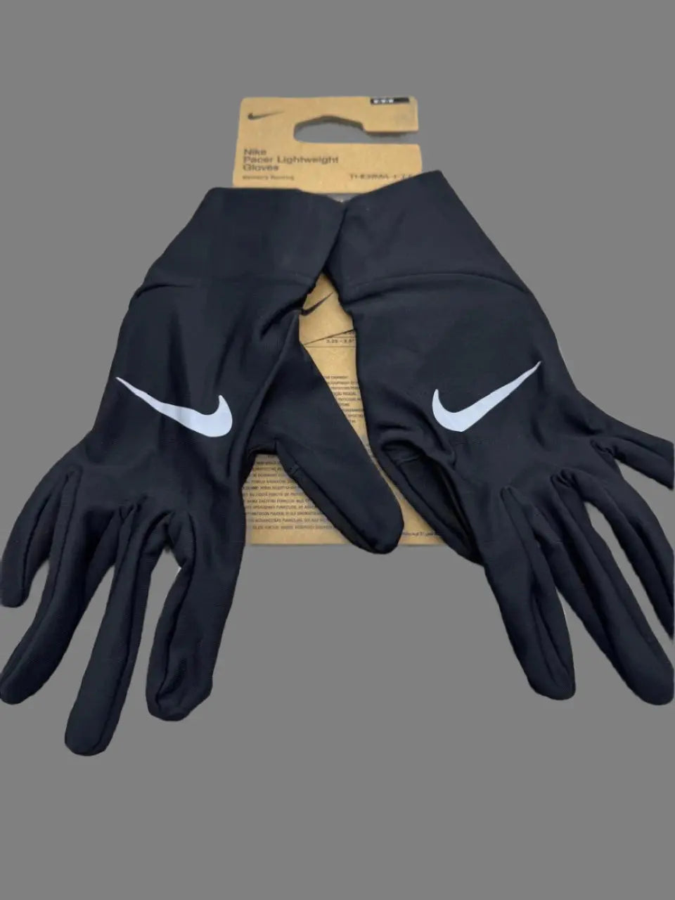 Black Nike gloves on a gray surface with packaging in the background